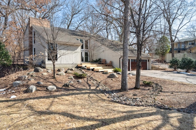 exterior space featuring a chimney, concrete driveway, and a garage