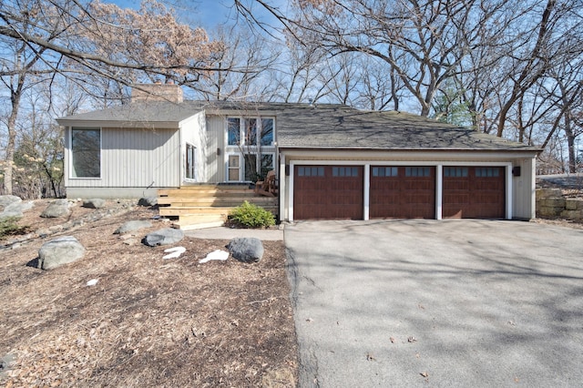 view of front of property with driveway, an attached garage, and a chimney