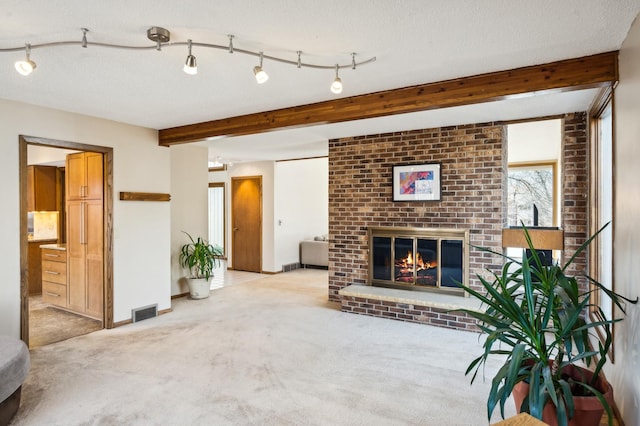 living room with visible vents, beamed ceiling, a textured ceiling, carpet floors, and a brick fireplace