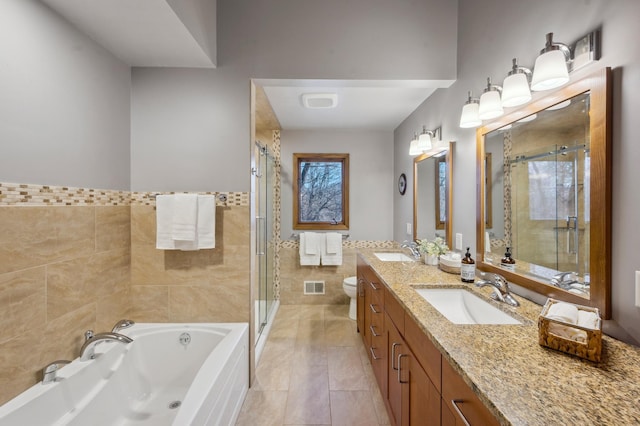 bathroom with a sink, visible vents, tile walls, and a stall shower