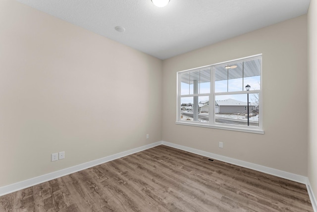 unfurnished room with visible vents, baseboards, and wood finished floors