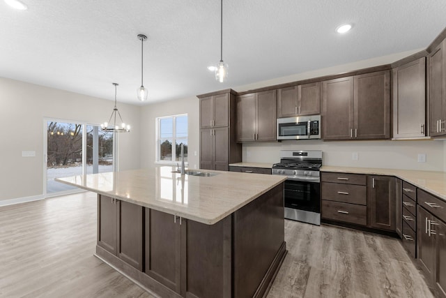 kitchen featuring dark brown cabinetry, light wood-style flooring, stainless steel appliances, and a sink