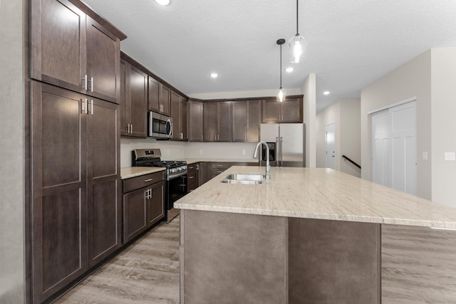 kitchen featuring a sink, decorative light fixtures, stainless steel appliances, dark brown cabinetry, and light wood finished floors