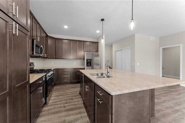 kitchen featuring light wood finished floors, dark brown cabinetry, appliances with stainless steel finishes, and a sink