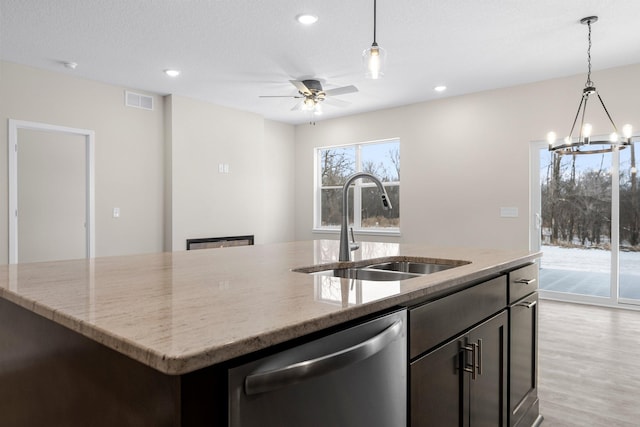 kitchen with light stone counters, visible vents, an island with sink, a sink, and stainless steel dishwasher