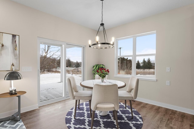 dining space with baseboards, an inviting chandelier, and light wood finished floors