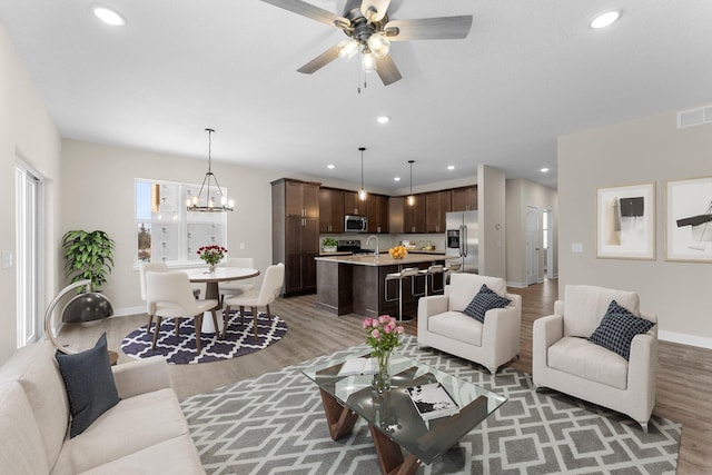 living room featuring light wood finished floors, visible vents, recessed lighting, and baseboards