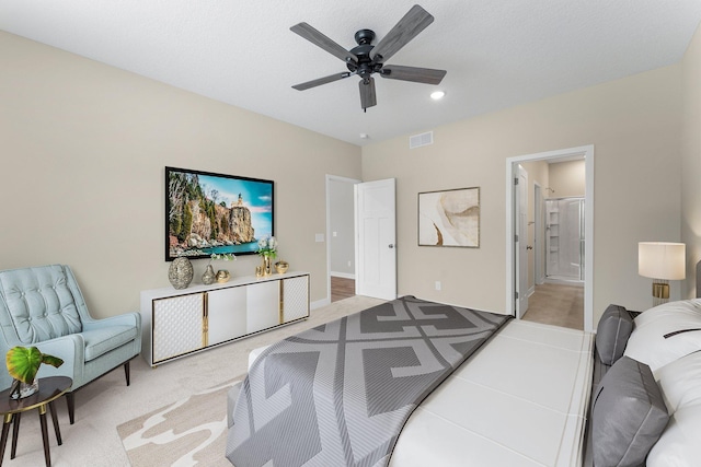 bedroom featuring light carpet, visible vents, ensuite bathroom, and ceiling fan