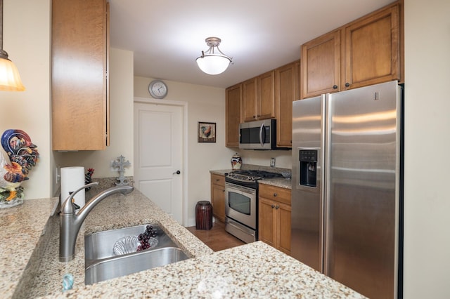 kitchen featuring a sink, brown cabinetry, light stone countertops, and stainless steel appliances