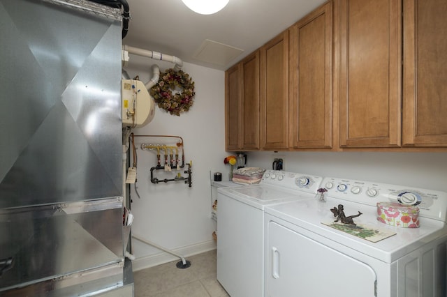 washroom with heating unit, washing machine and dryer, cabinet space, light tile patterned flooring, and baseboards