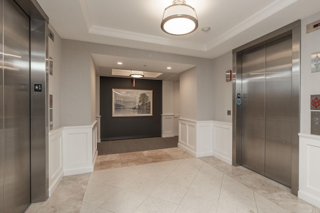 hall with elevator, wainscoting, and a raised ceiling