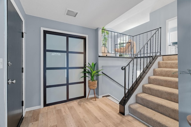 entrance foyer with stairs, wood finished floors, and baseboards