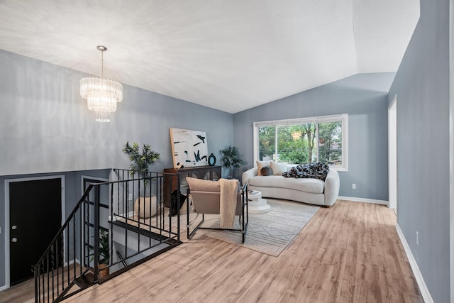 living area with a chandelier, baseboards, wood finished floors, and vaulted ceiling