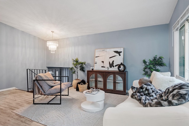 sitting room with baseboards, an upstairs landing, a notable chandelier, and wood finished floors