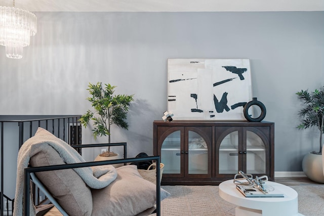 living area featuring baseboards and a chandelier