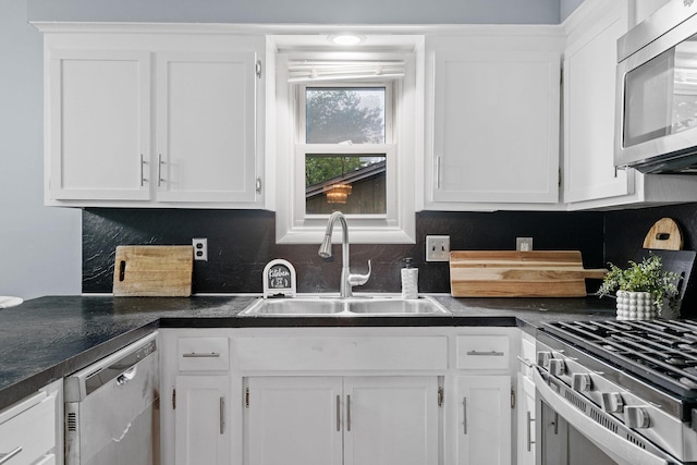 kitchen with dark countertops, tasteful backsplash, appliances with stainless steel finishes, white cabinets, and a sink