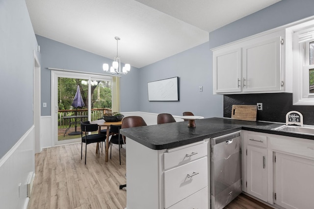 kitchen with dark countertops, white cabinets, a peninsula, and stainless steel dishwasher