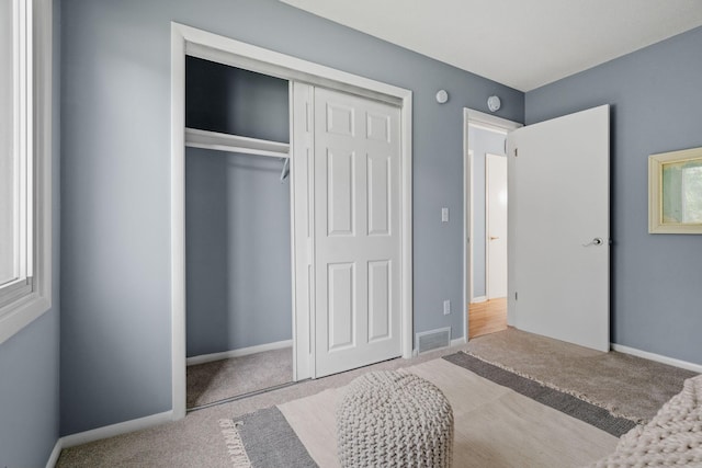 carpeted bedroom featuring a closet, visible vents, and baseboards