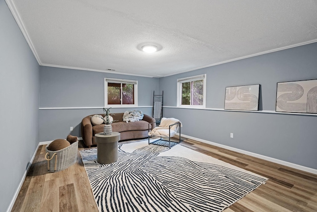 living room with crown molding, wood finished floors, baseboards, and a textured ceiling