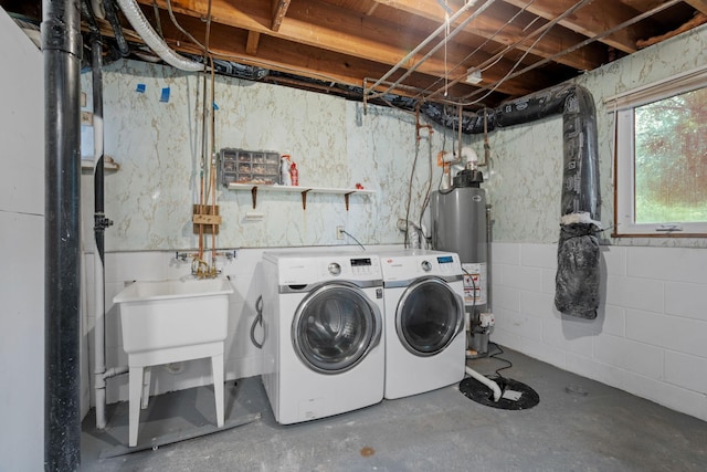 clothes washing area featuring gas water heater, a sink, laundry area, and washer and clothes dryer