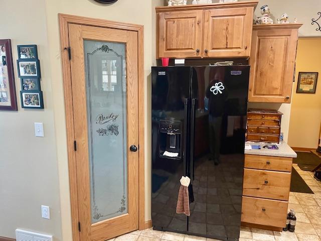 kitchen featuring visible vents, light countertops, and black refrigerator with ice dispenser