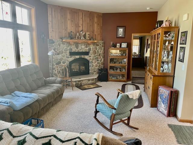 carpeted living room with a stone fireplace