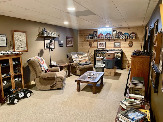 living room featuring wooden walls, a paneled ceiling, and carpet floors