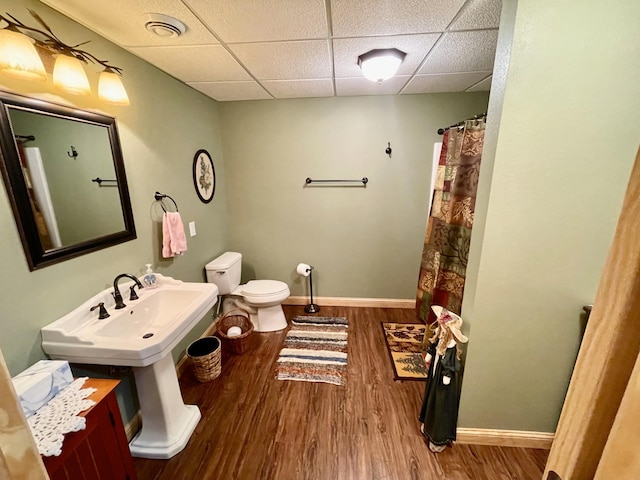 full bath featuring a drop ceiling, baseboards, toilet, and wood finished floors