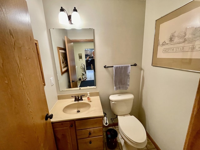 half bathroom with baseboards, toilet, and vanity