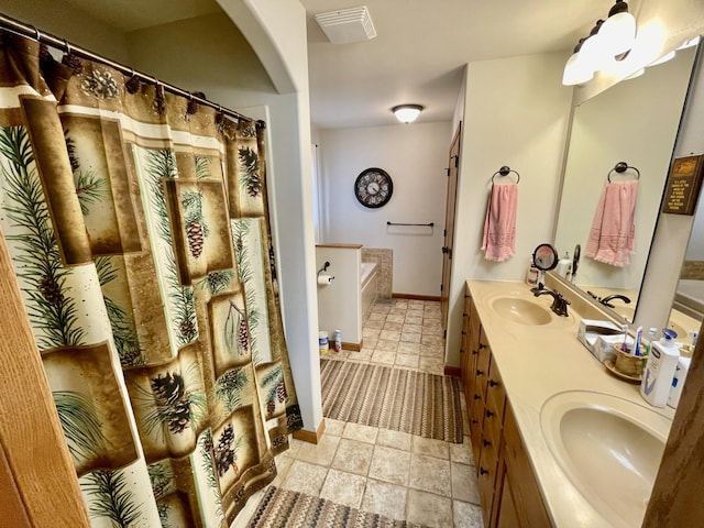 bathroom featuring a bath, double vanity, baseboards, and a sink