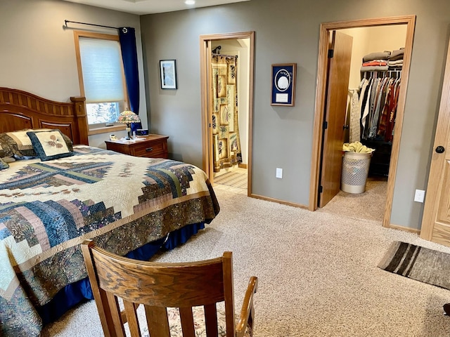 carpeted bedroom featuring a closet, ensuite bath, a walk in closet, and baseboards