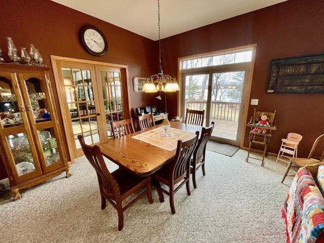 dining space with light colored carpet, french doors, and an inviting chandelier