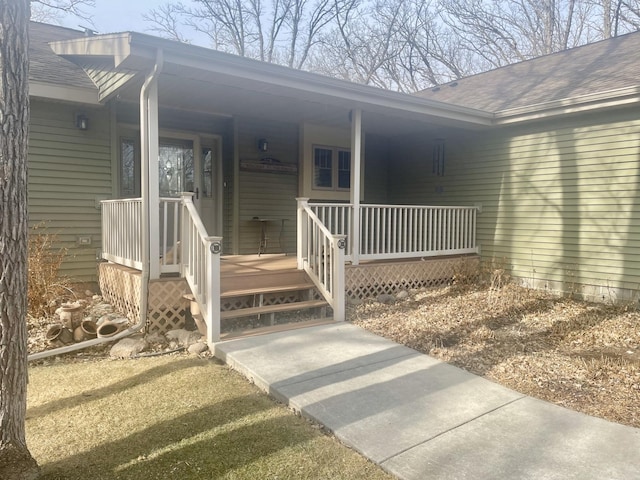 entrance to property featuring covered porch and roof with shingles