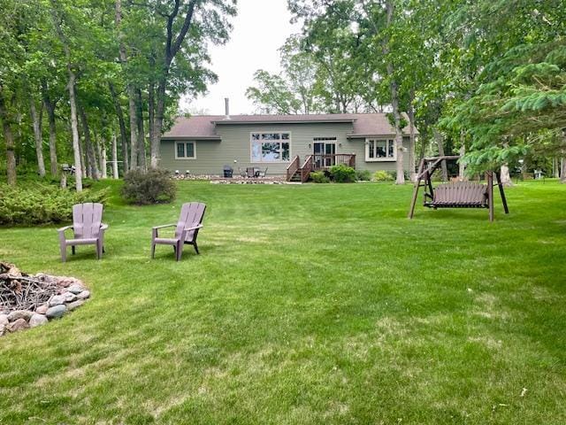 26909 Lake Ethel Rd, Girard Twp, MN 56515 - back of property featuring an outdoor fire pit, a deck, and a lawn