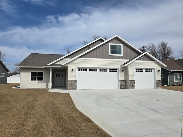 craftsman-style house with board and batten siding, a front lawn, concrete driveway, a garage, and stone siding