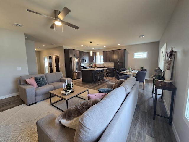 living area with light wood-type flooring, visible vents, baseboards, and a wealth of natural light