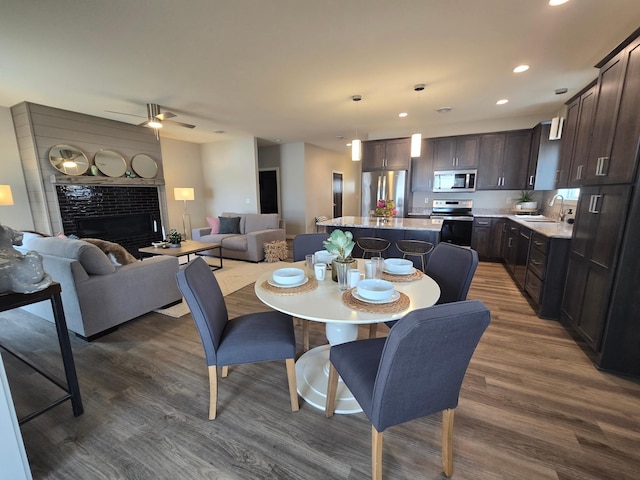 dining space featuring recessed lighting, a fireplace, dark wood-type flooring, and a ceiling fan