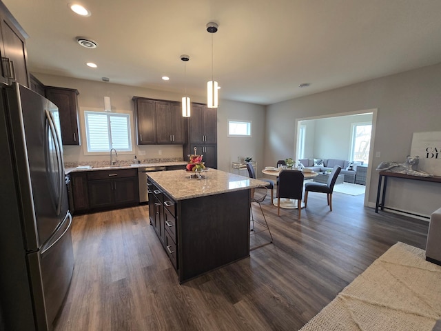 kitchen with a kitchen island, open floor plan, stainless steel appliances, dark brown cabinetry, and dark wood-style flooring