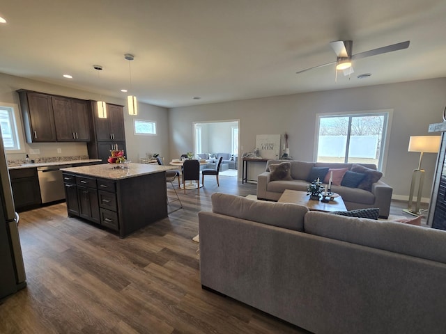 living room with a healthy amount of sunlight, a ceiling fan, and dark wood-style flooring