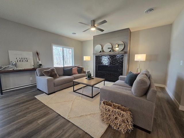 living area featuring visible vents, baseboards, a tile fireplace, wood finished floors, and a ceiling fan