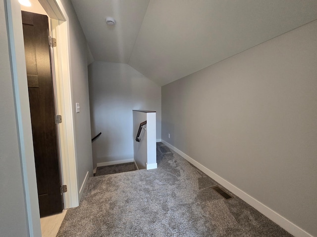 interior space featuring visible vents, baseboards, carpet flooring, and vaulted ceiling