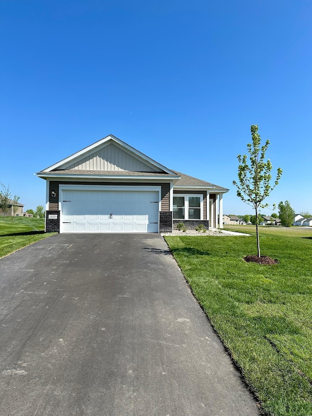 view of front of property with aphalt driveway, stone siding, an attached garage, and a front yard