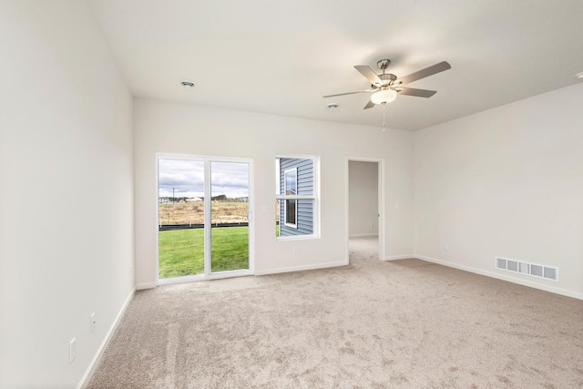 carpeted spare room featuring baseboards, visible vents, and ceiling fan