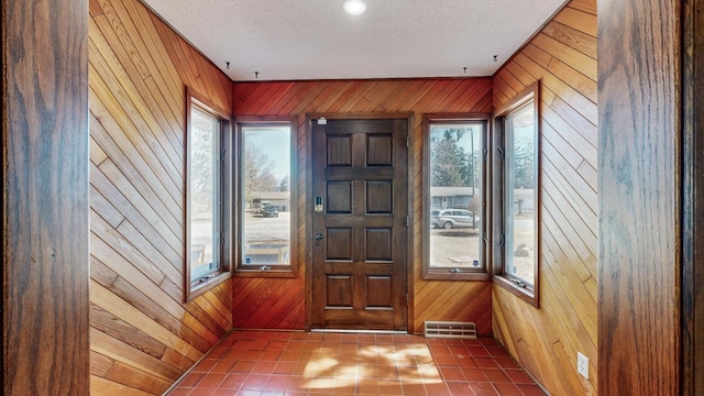 entryway with a wealth of natural light, visible vents, and wood walls