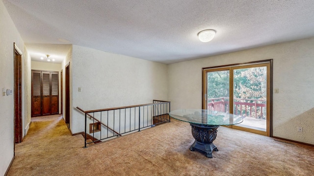 unfurnished room with baseboards, carpet floors, a textured ceiling, and a textured wall