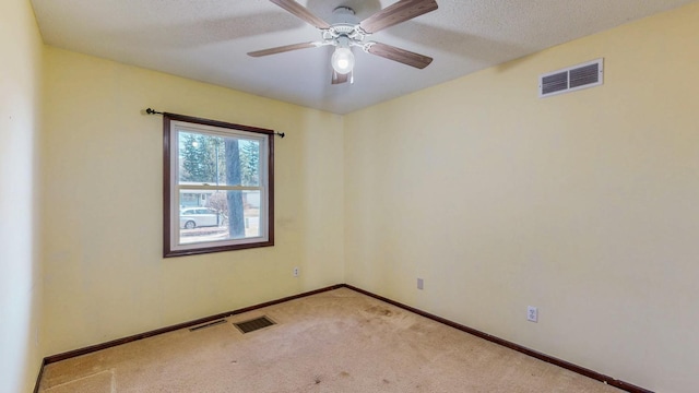 spare room with visible vents, light colored carpet, baseboards, and ceiling fan