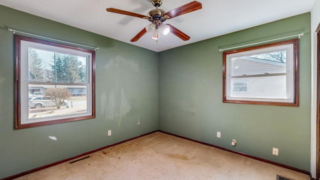 unfurnished room featuring light colored carpet, visible vents, a wealth of natural light, and baseboards