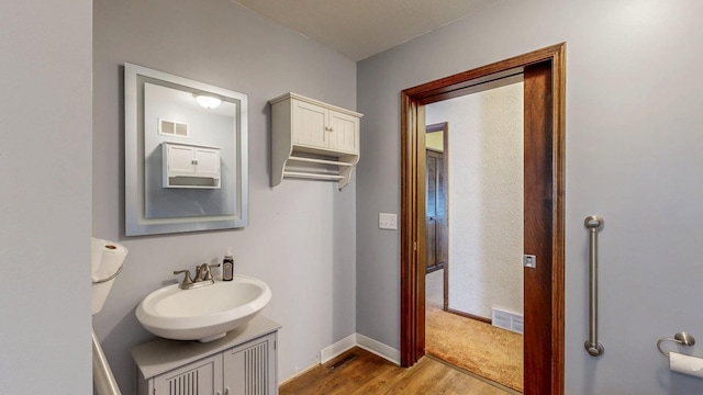 bathroom featuring visible vents, vanity, baseboards, and wood finished floors