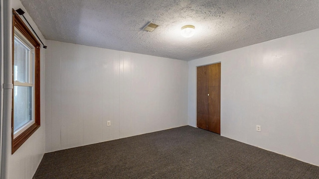 carpeted empty room featuring visible vents and a textured ceiling