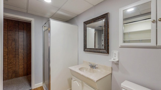 full bathroom featuring a drop ceiling, toilet, a stall shower, and vanity